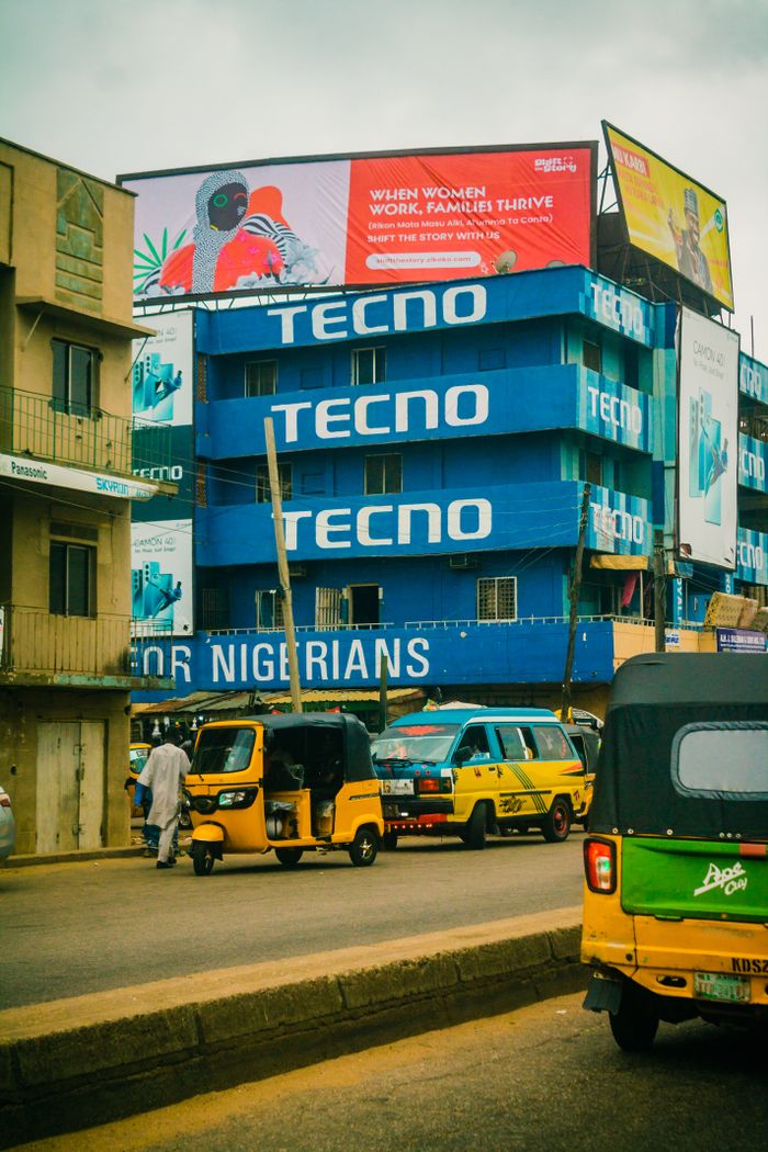 Oferty Vibrant street with vehicles in Kaduna, Nigeria, showcasing local life and advertising.